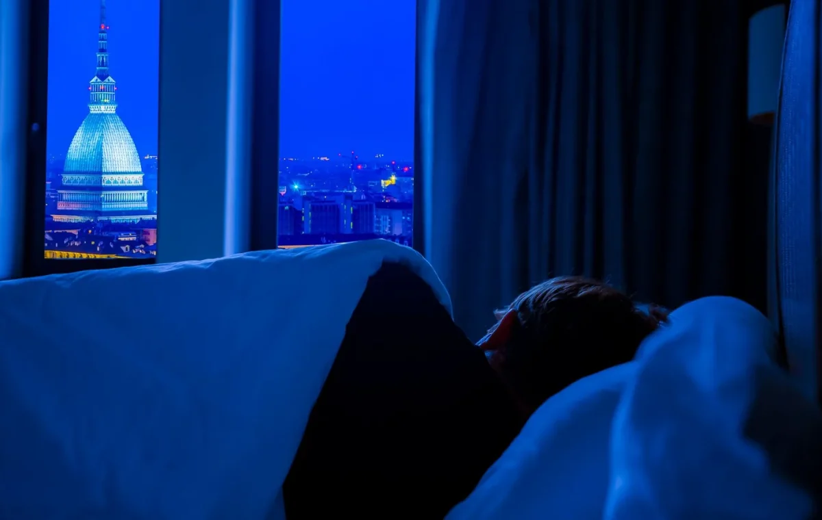 A serene view of Turin's night skyline featuring Mole Antonelliana, seen from a cozy bedroom.