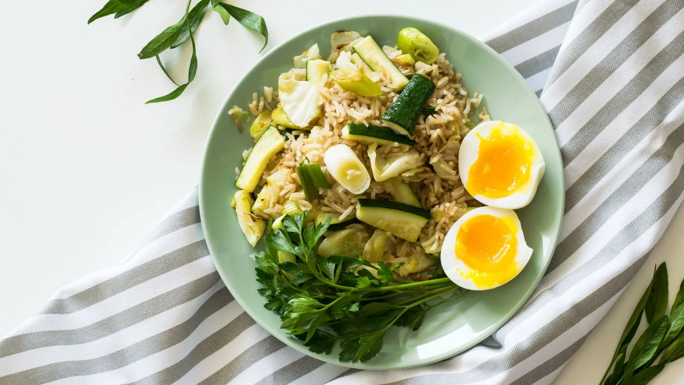 Delicious rice meal with zucchini, greens, and soft-boiled egg, perfect for a healthy diet.