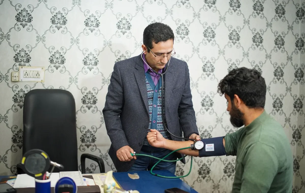 Doctor checking patient's blood pressure during medical consultation indoors.