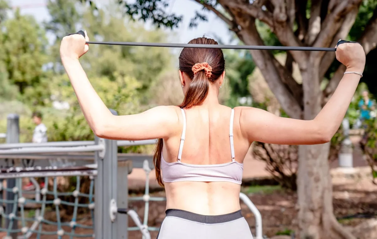 Woman using a resistance band for workout at an outdoor gym, showcasing healthy and active lifestyle.
