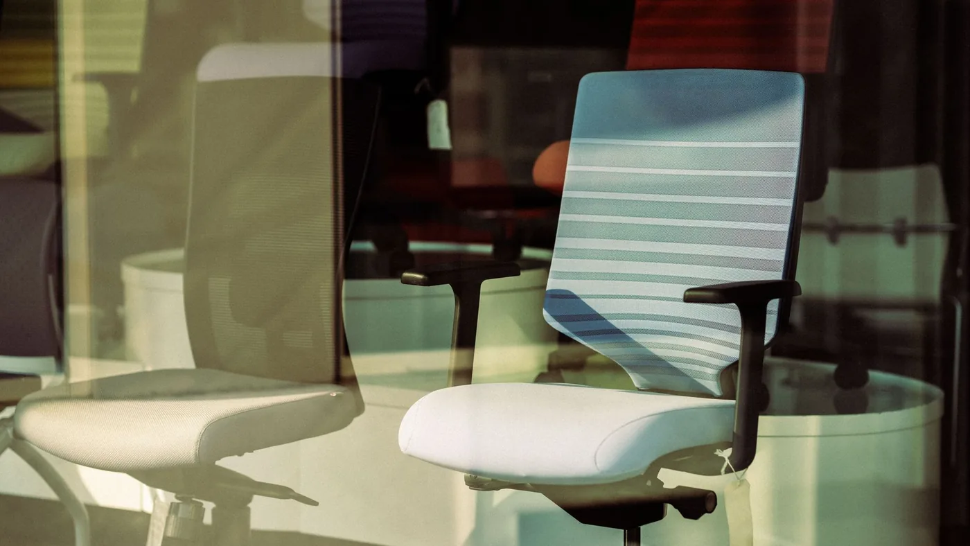 Contemporary office chairs displayed behind glass, offering modern ergonomic solutions for workspace.