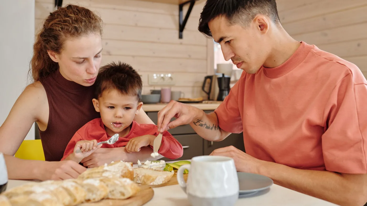 Parents and child bonding over breakfast indoors, capturing family togetherness.