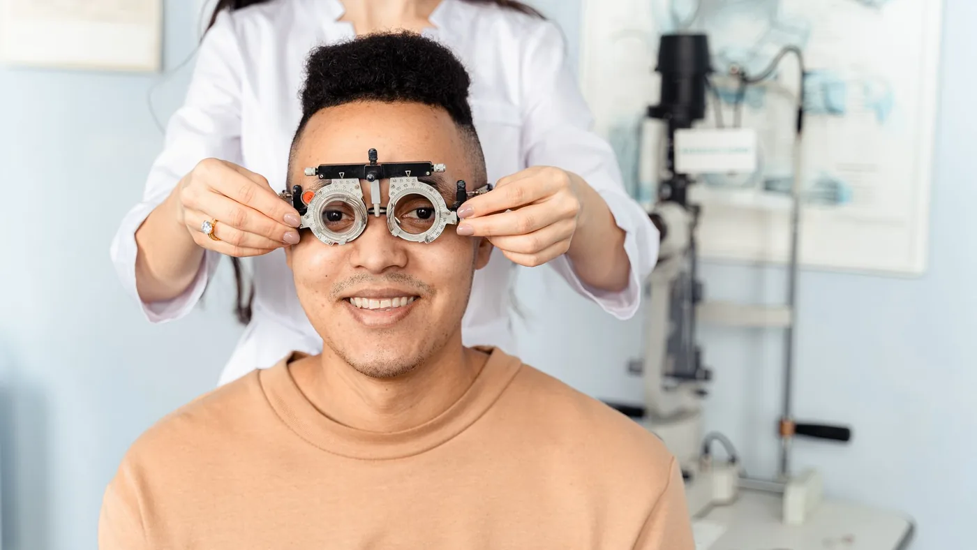 A man receiving an eye exam with a phoropter in an optometry clinic setting.