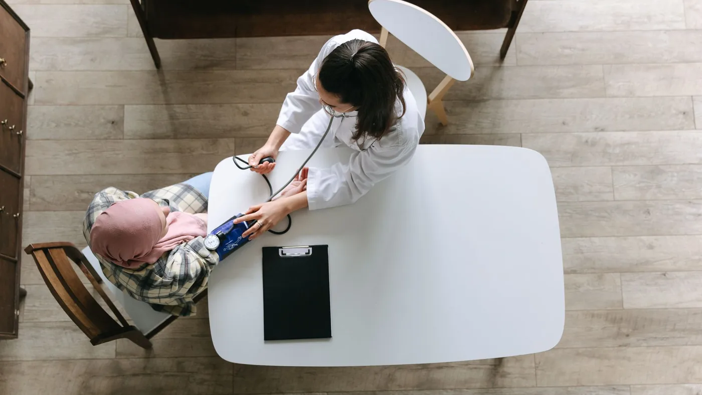 Overhead view of a doctor checking a patient's blood pressure during a healthcare consultation indoors.