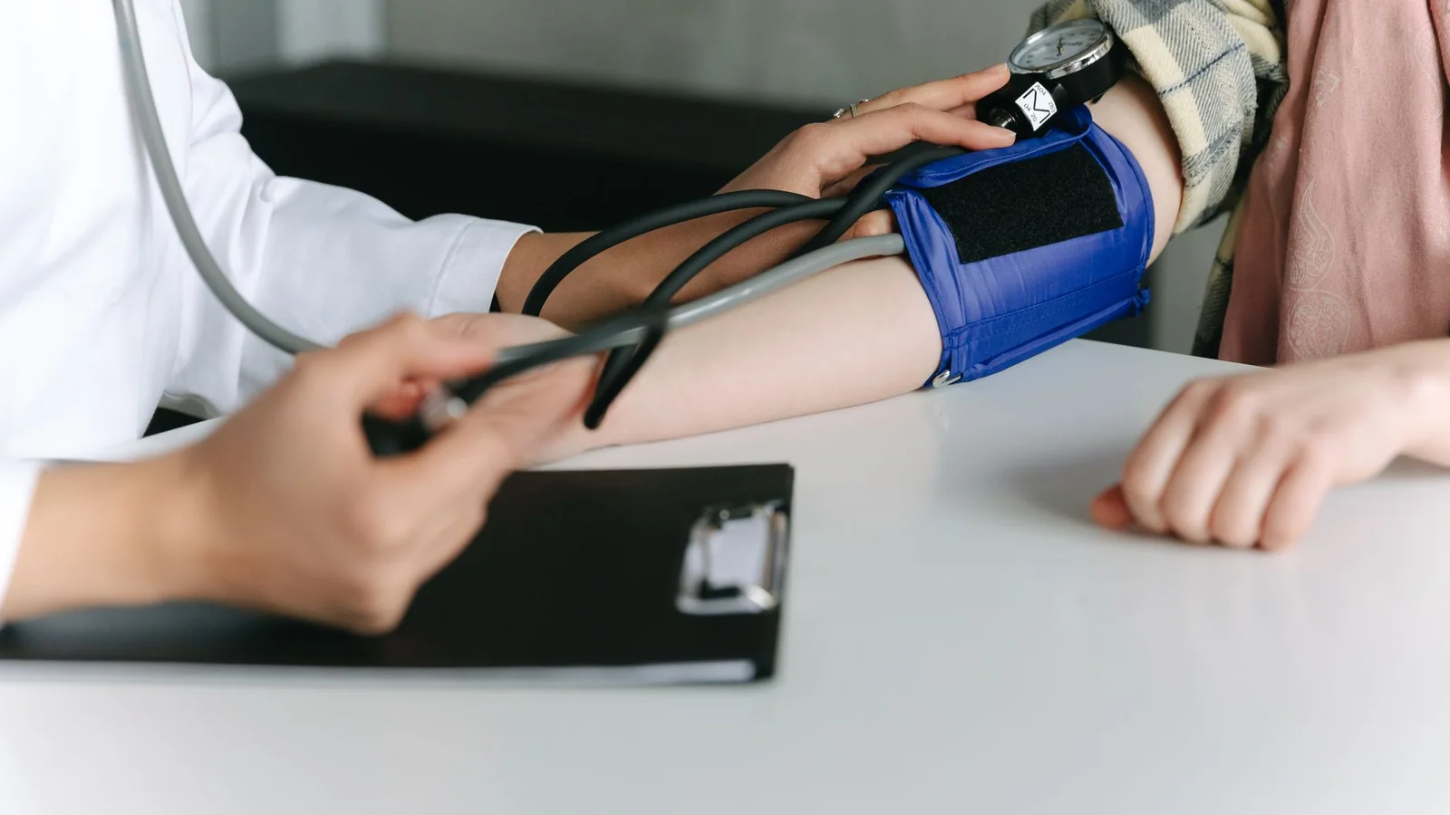 A healthcare worker uses a sphygmomanometer to check a patient's blood pressure in a medical office.