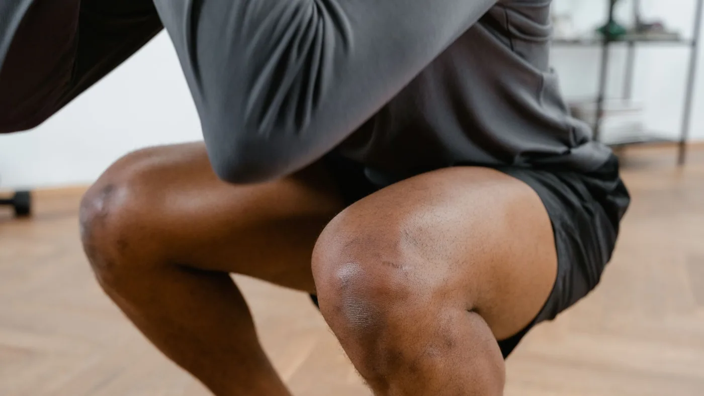 A focused view of a male athlete performing squats in a gym setting, emphasizing fitness and strength.
