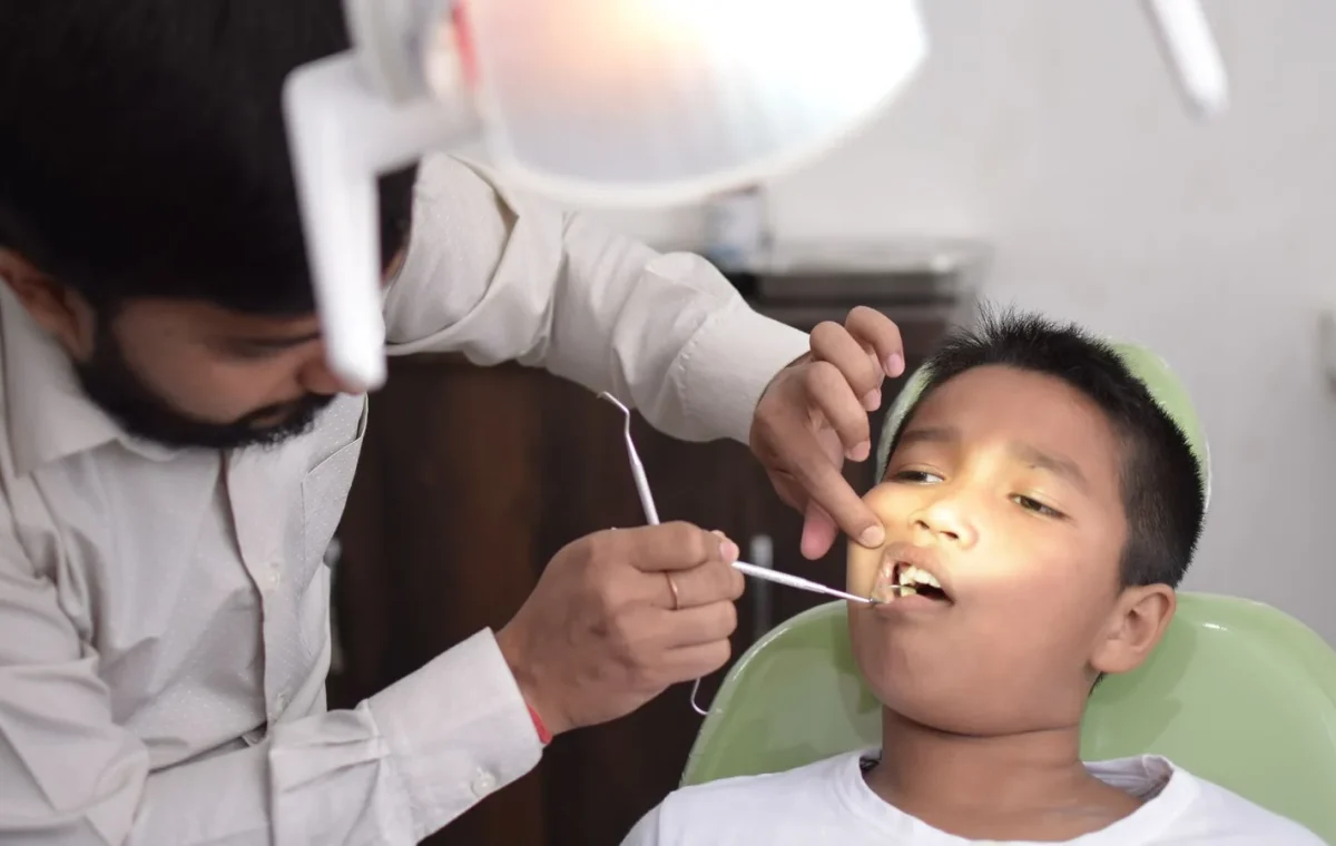 A dentist checks a child's teeth in a well-lit dental clinic, focusing on oral care.