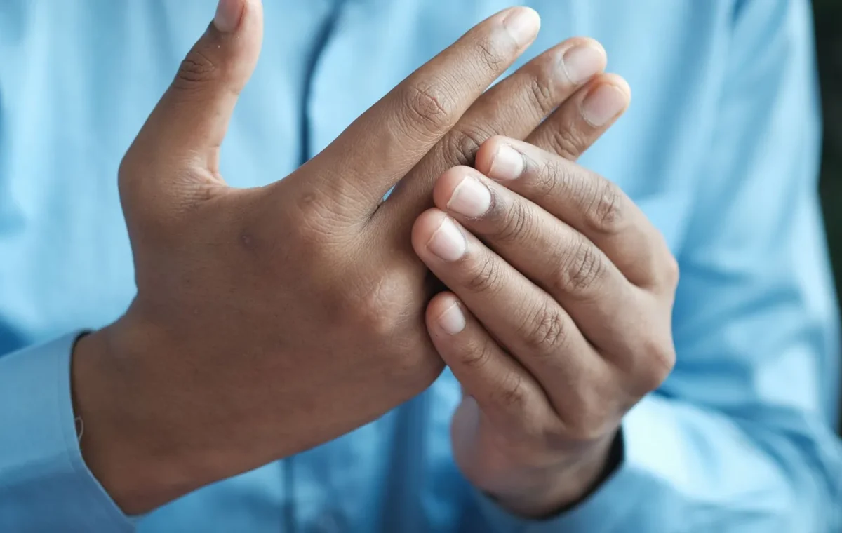 Close-up of a man gently holding his hand, symbolizing comfort or pain relief.