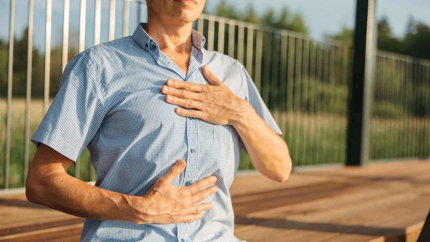 A man practicing relaxation with hands on chest and abdomen outdoors.