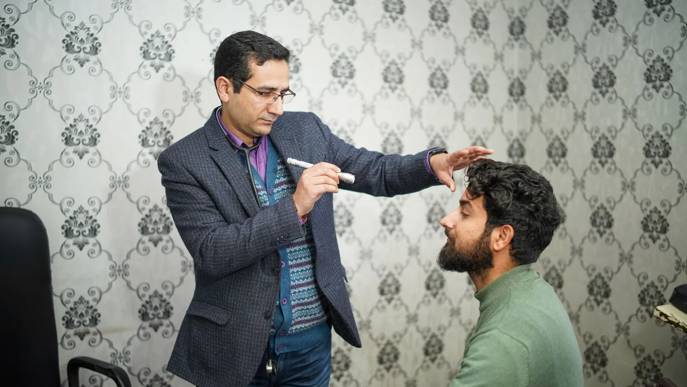 A doctor performs an eye examination on a patient in a clinical setting.