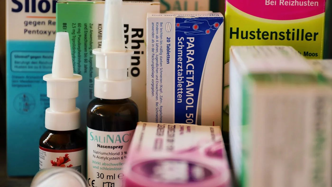 Assortment of cold and flu medications on a pharmacy counter.