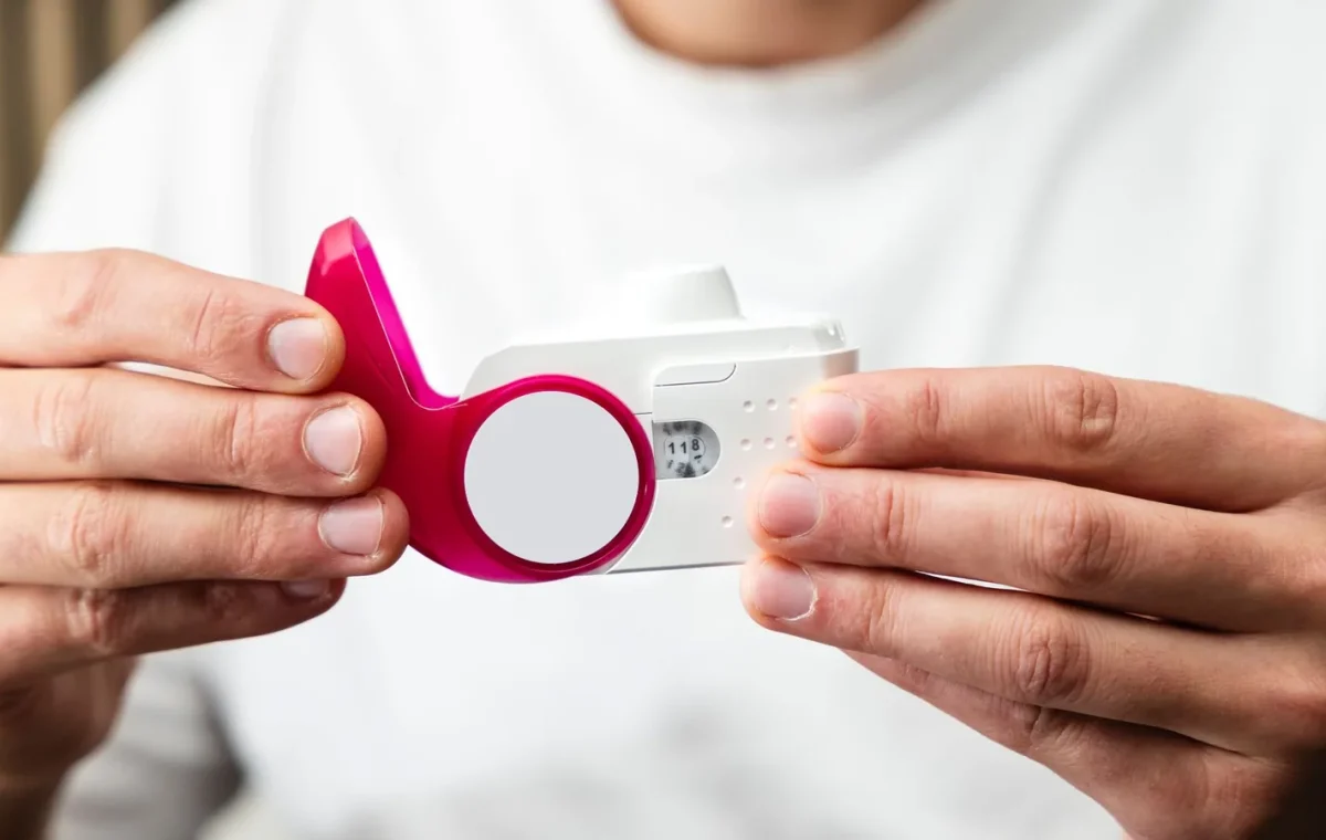 Close-up of hands holding a peak flow meter for respiratory health monitoring.