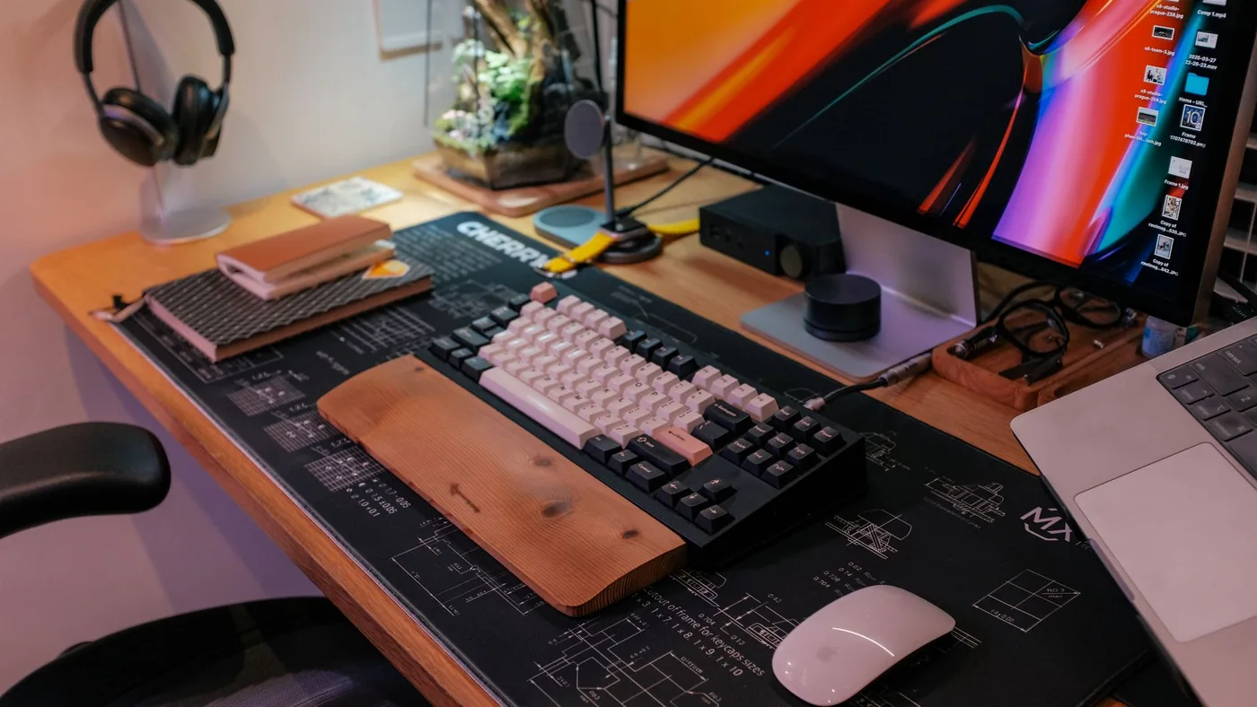 A stylish workspace featuring a modern keyboard, monitor, and essentials neatly arranged.