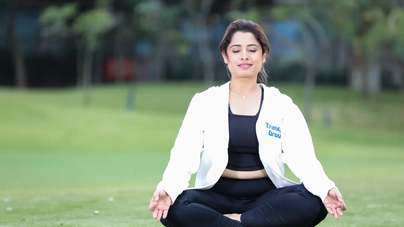 Young woman practicing meditation in a park, embodying calmness and relaxation on a sunny day.
