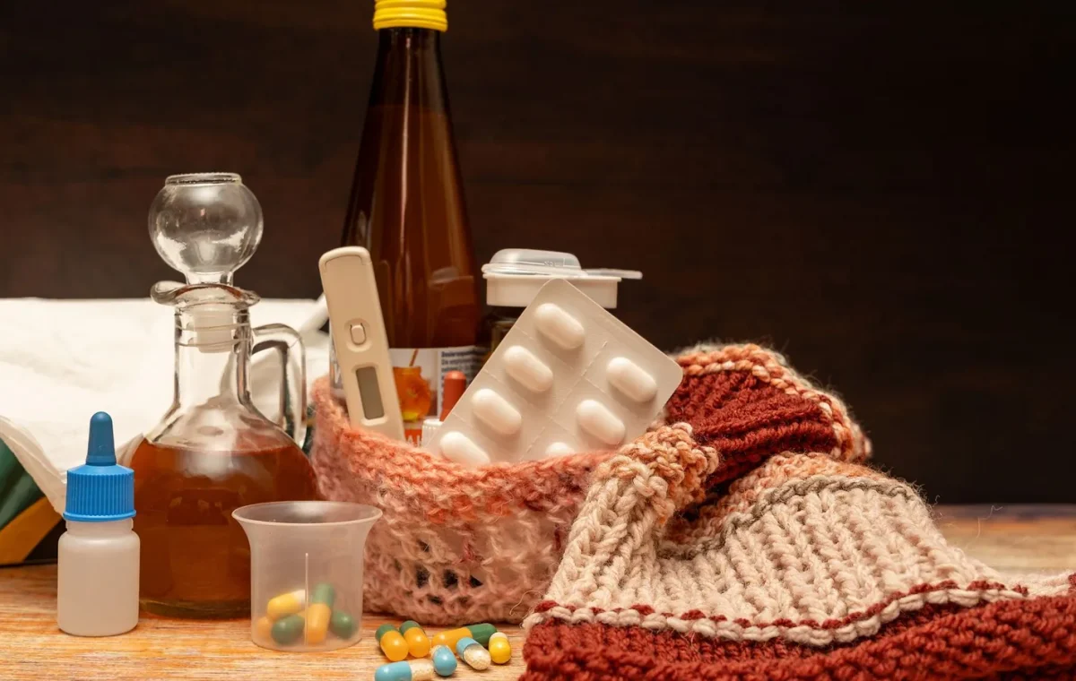 A warm collection of medications and items for cold and flu relief set on a wooden surface.