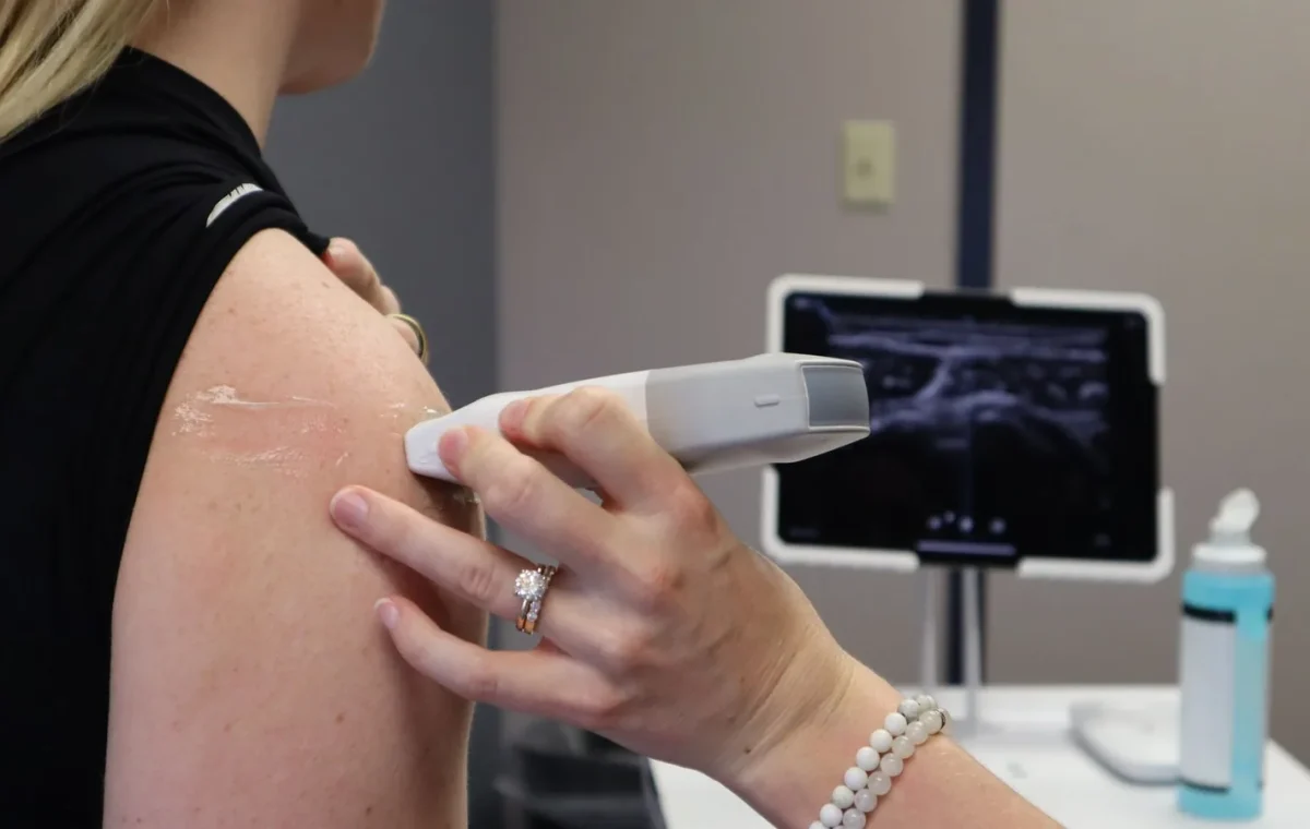 Healthcare professional conducting an ultrasound on a shoulder injury in a medical office.