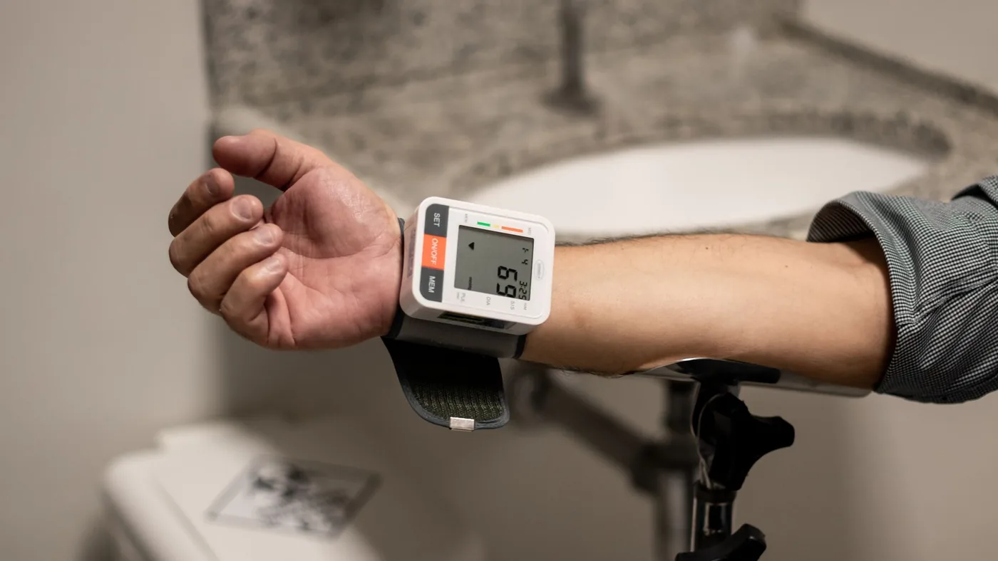 Close-up of an arm using a wrist sphygmomanometer in a healthcare setting.