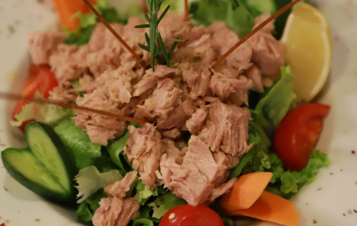 Close-up of a fresh tuna salad with vegetables and lemon garnish.