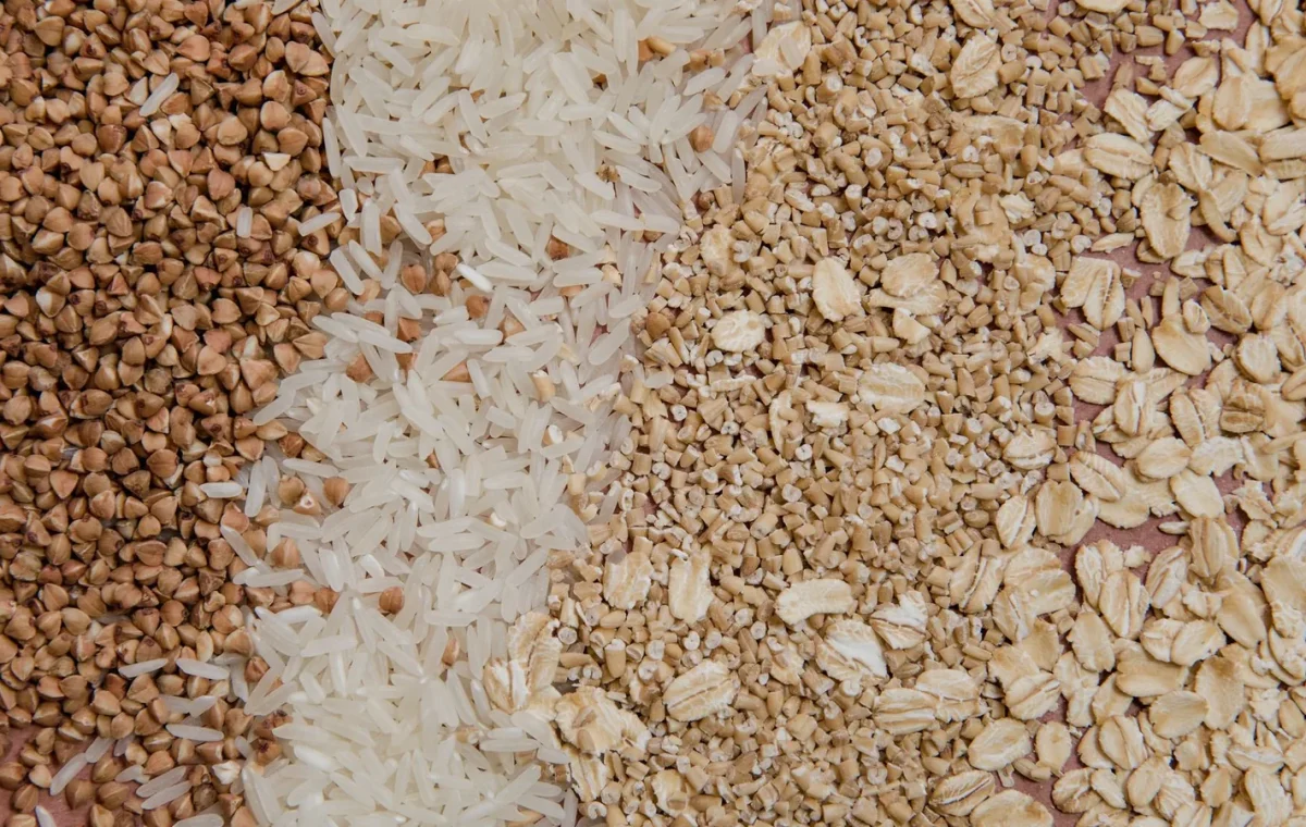 A variety of grains and cereals including oats, rice, and buckwheat arranged in a flat lay.